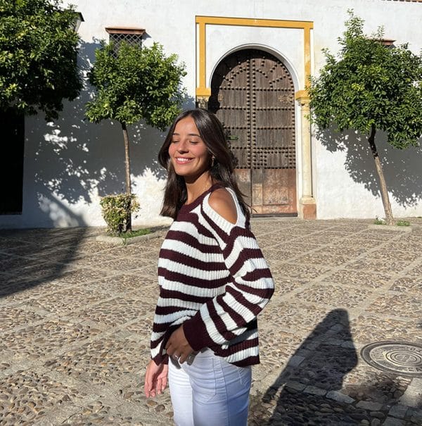 chica sonriendo con un jersey rayas burdeos y blanco con hombros descubiertos