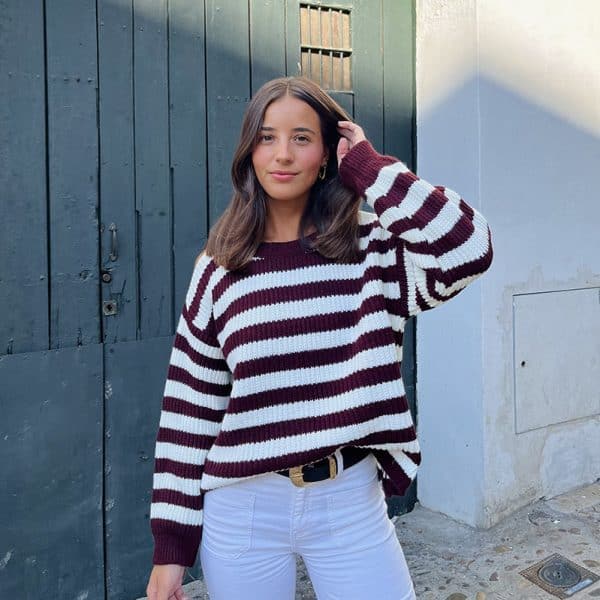 chica sonriendo con un jersey rayas burdeos y blanco con hombros descubiertos