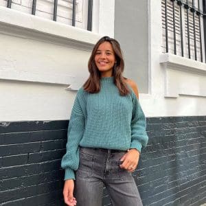 chica sonriendo con un jersey verde con el hombro izquierdo descubierto