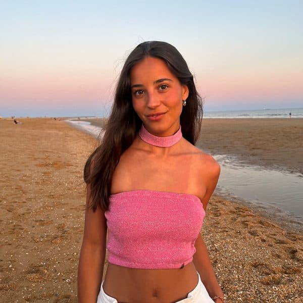 chica en la playa con una banda rosa con brillo plateado y choker del mismo tejido en el cuello