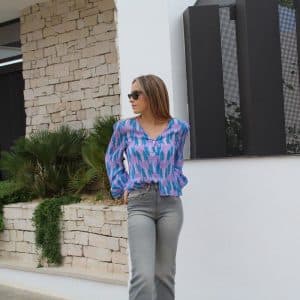 chica mirando a un lado con una blusa en tonos lilas con lurex plata y pantalón gris con tachuelas laterales