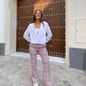 chica con blusa blanca cruzada en bajo y pantalón fluido blanco con print burdeo