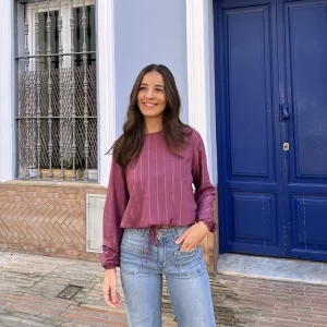 chica posando en la calle con mano en el bolsillo y blusa rosa