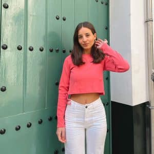 chica con camiseta corta manga larga coral con frunce en lateral derecho y pantalón blanco