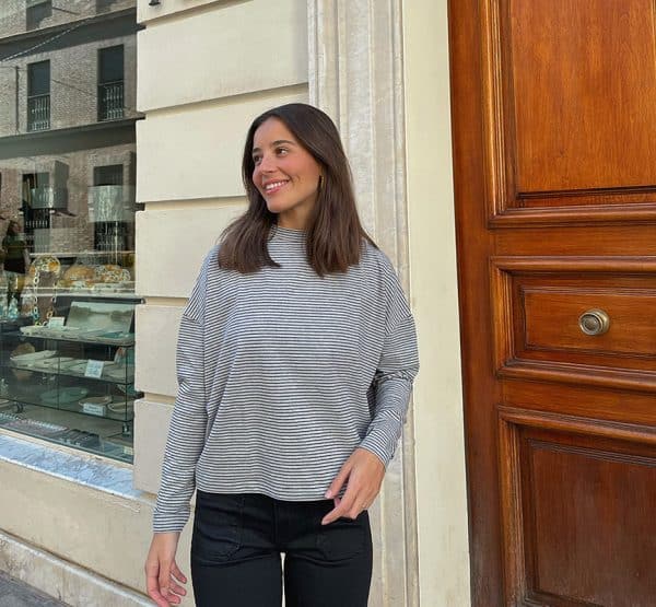 chica sonriendo con una camiseta oversize gris con rayas negras