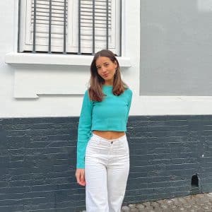 chica con pantalón blanco y camiseta verde agua con un cordón para fruncir el lateral derecho