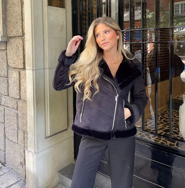 chica en la calle posando con una mano en el pelo y otra en el bolsillo de una chaqueta negra de doble faz