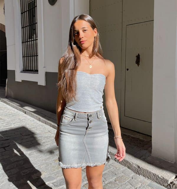 chica con falda tejana gri s y desflecada en bajo con top plata