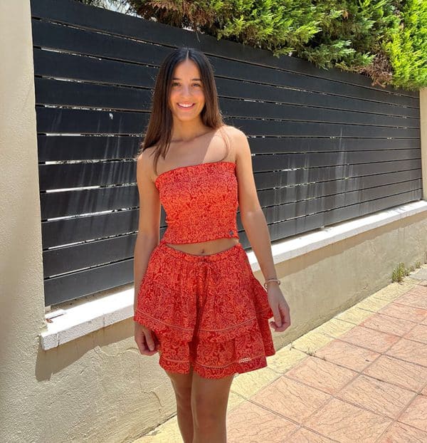 chica en la calle con un conjunto de top y falda de color coral