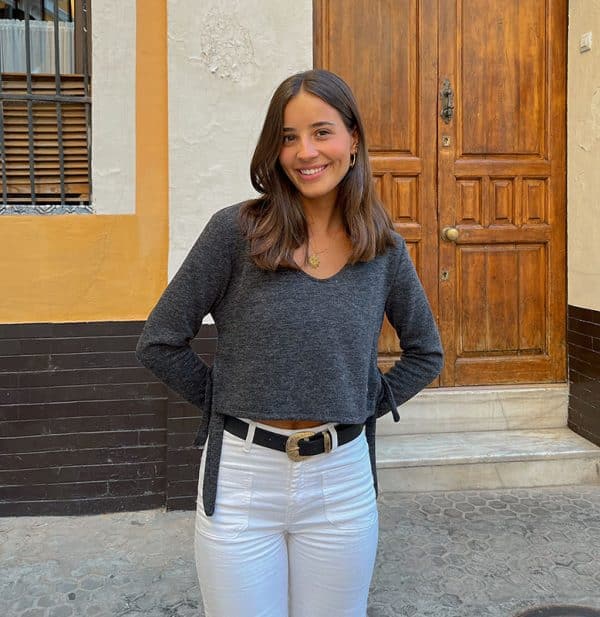 chica sonriendo con jersey cuello pico corto gris antracita con aberturas laterales con tiras para atar