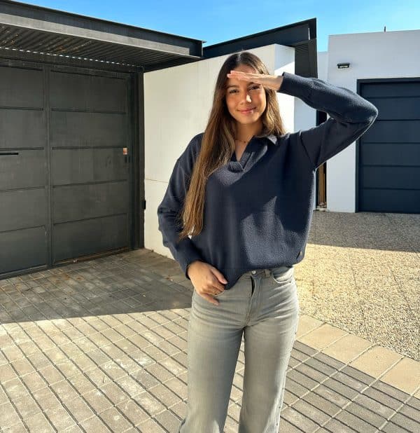 chica sonriendo con un jersey cuello polo en antracita y pantalón tejano gris con tachuelas en laterales y bolsillos