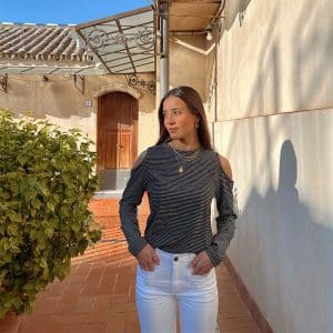 chica con camiseta negra de rayas blancas con hombros descubiertos.