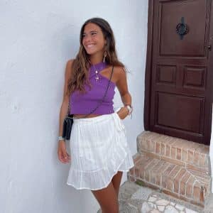 influencer Mercedes Sierra con un top corto morado y falda corta blanca con hilo de lurex