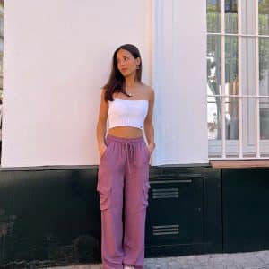 chica delante de una pared blanca vestida con un pantalón fluido rosa cargo y top tricot blanco