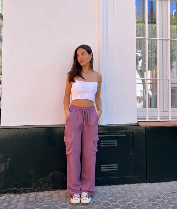 chica delante de una pared blanca vestida con un pantalón fluido rosa cargo y top tricot blanco