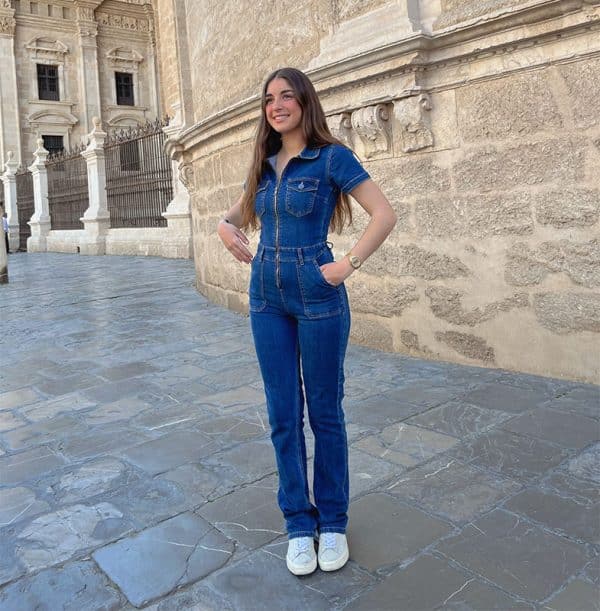 chica sonriendo con las manos en los bolsillos con un mono tejano azul oscuro