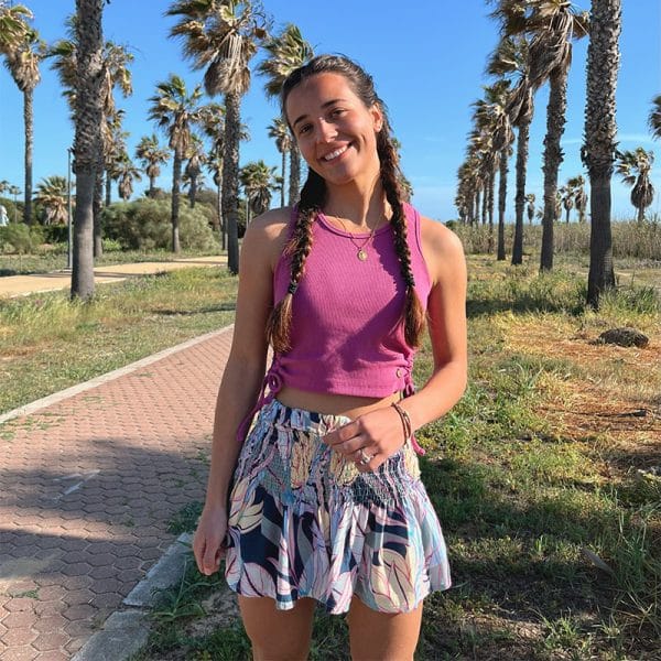 chica sonriendo en un paseo con plameras con un top fucsia y un short de flores