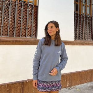 chica sonriendo con una sudadera azul con print crudo en pecho izquierdo y brazo derecho