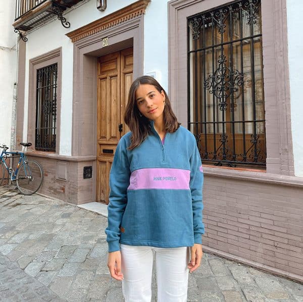 chica en la calle con una sudadera verde azulado con pieza frontal en lila con bordado pink pomelo y media cremallera