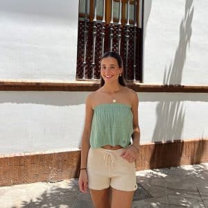 chica en la calle con un top palabra de honor verde con círculos de hilos plateados y dorados y un short de tricotosa crudo