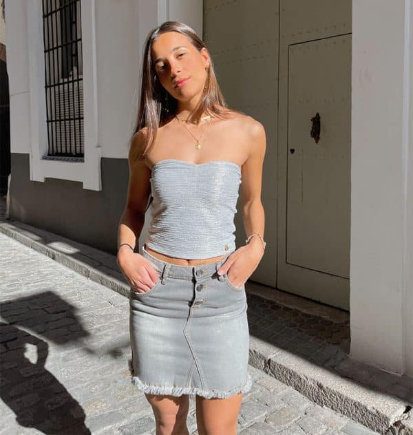 chica con falda tejana gri s y desflecada en bajo con top plata