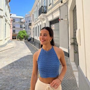 chica en una calle peatonal con un top de punto azul anudado al cuello