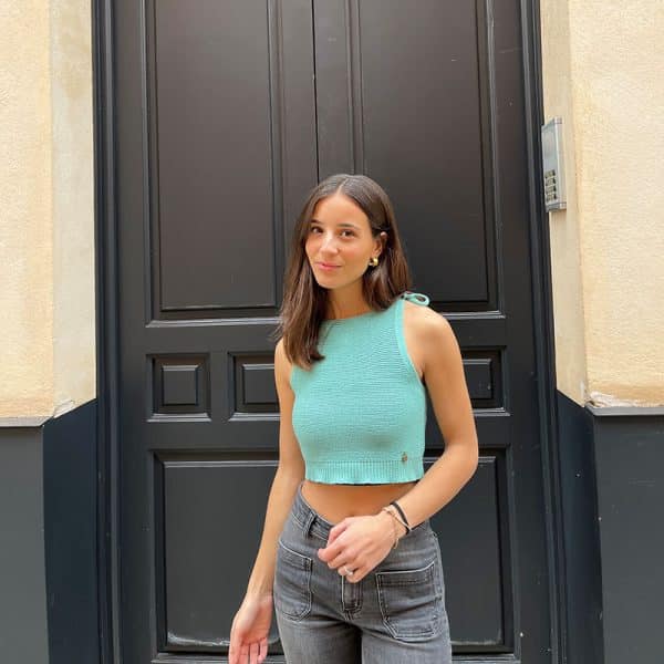 chica en la calle delante de una puerta verde sonriendo con un top de tirantes de tricotosa atado en tirantes en color verde wasabi