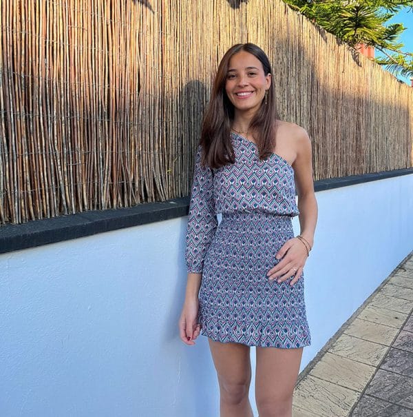 chica con un vestido asimétrico estampado en tonos berenjena y verde en fondo blanco