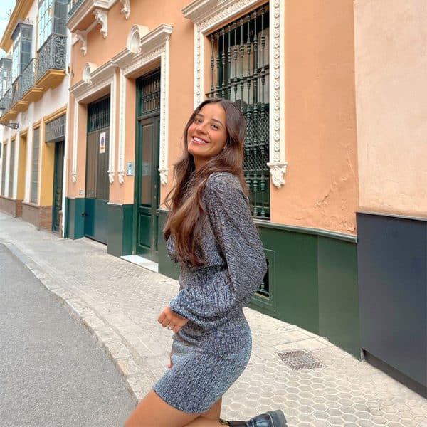 chica sonriendo con un vestido corto de fiesta plata con hilo metalizado